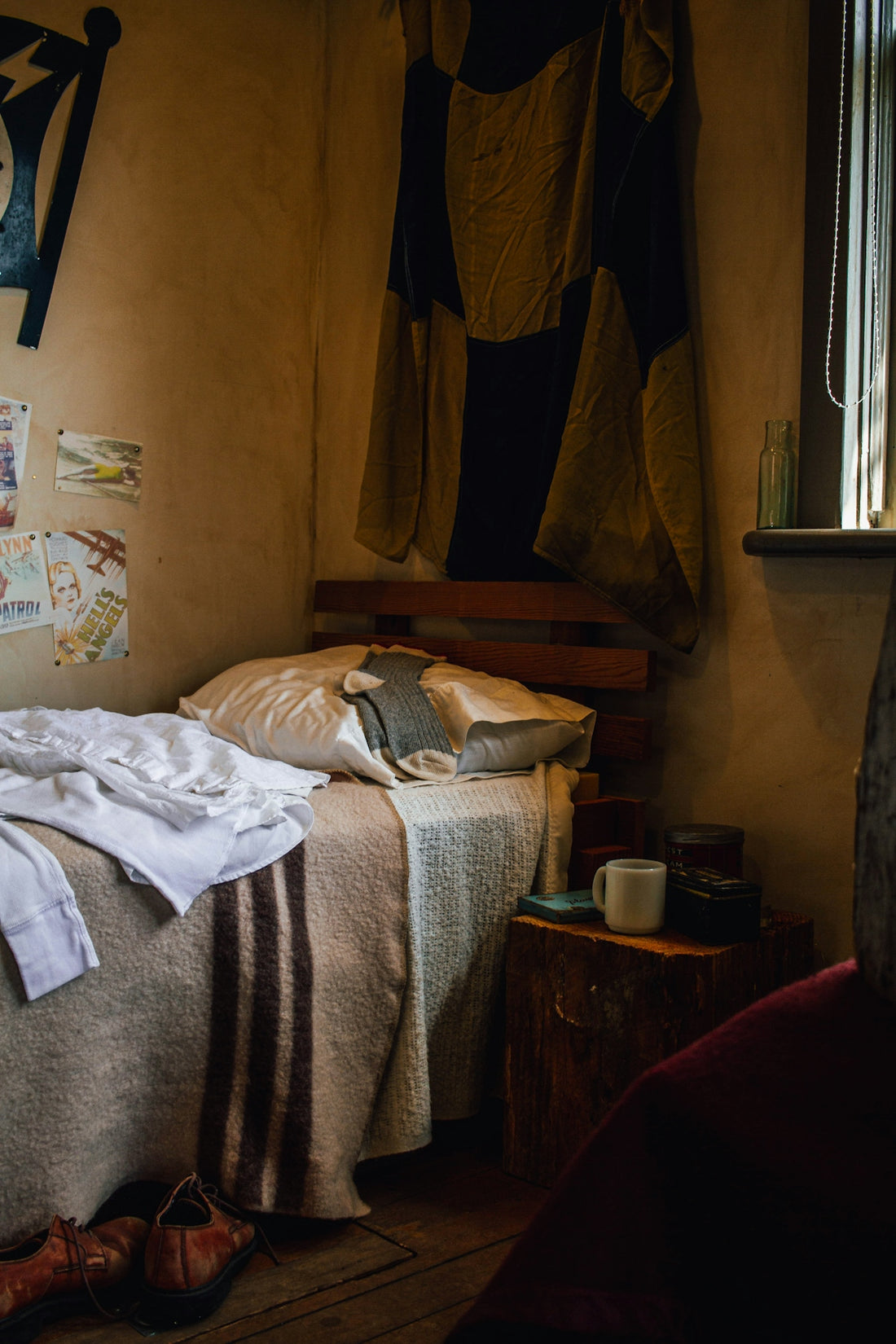 An unmade bed in a rustic, dimly lit bedroom