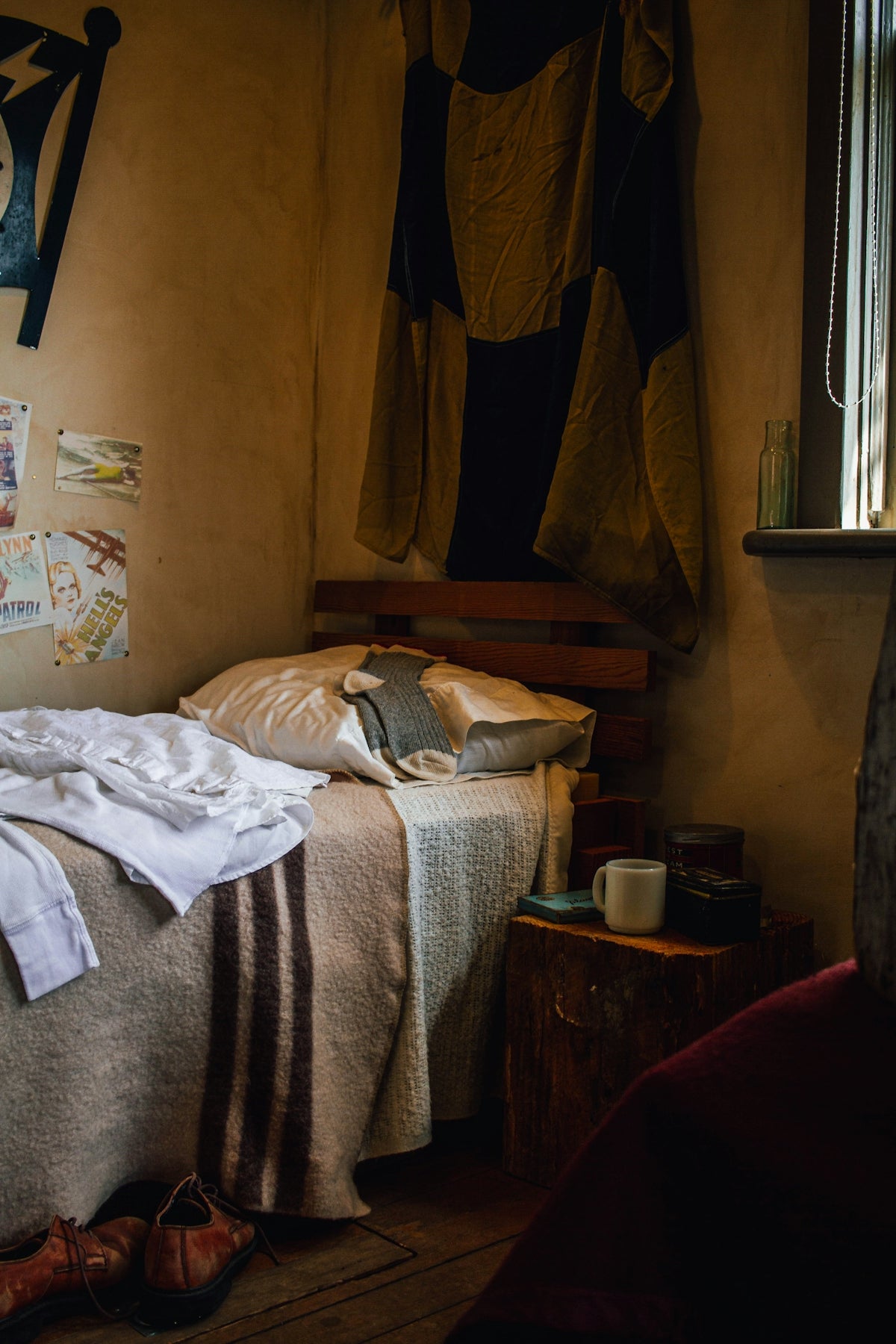 An unmade bed in a rustic, dimly lit bedroom